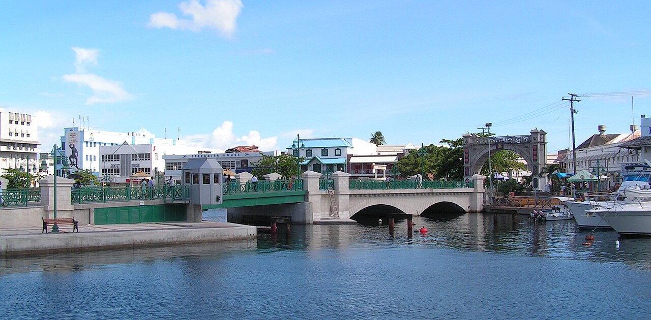 The Chamberlain Bridge over the Careenage in Bridgetown with the Independence Arch, moored boats and low buildings under a blue sky