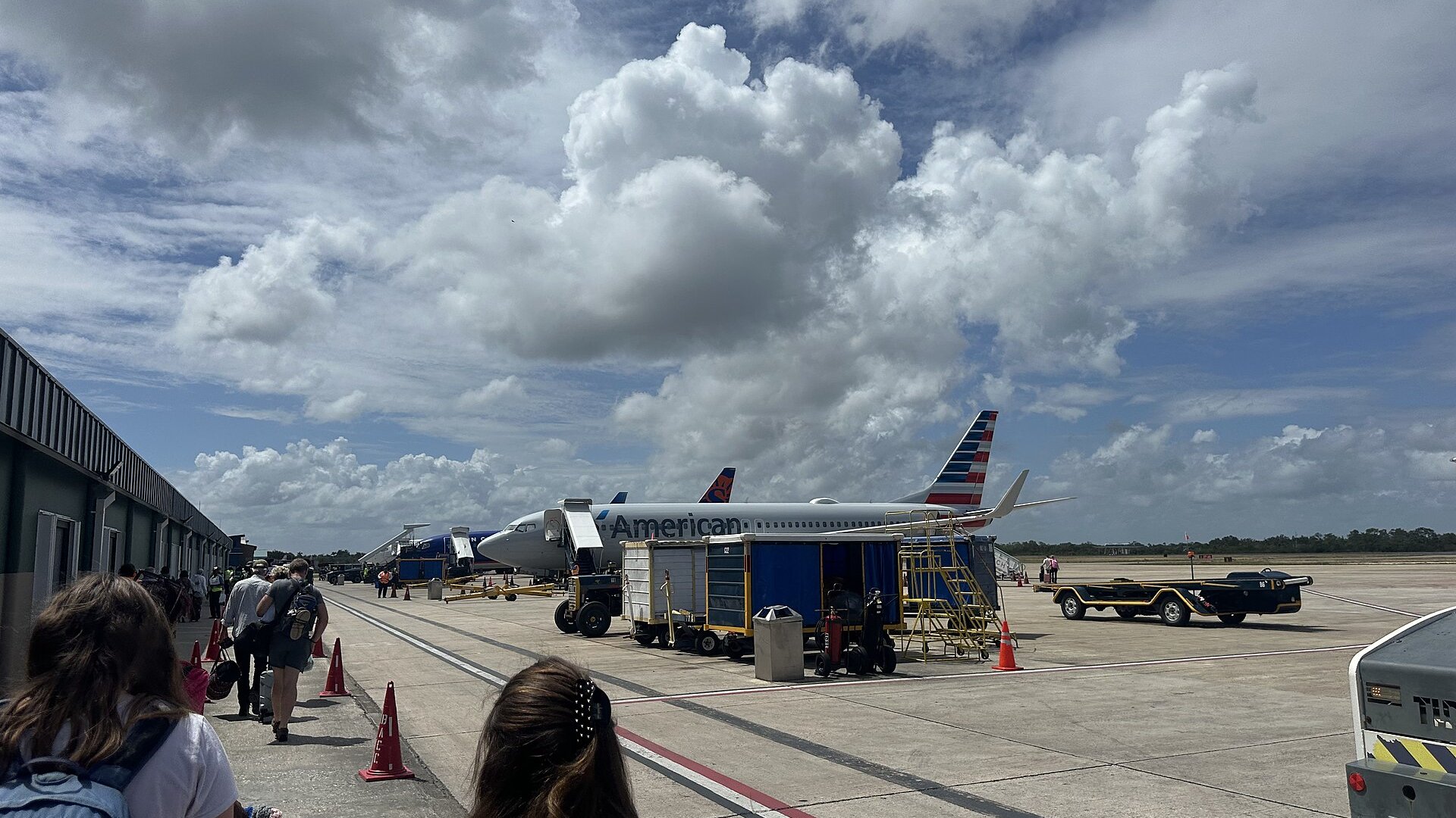 Passengers walking across the apron at Belize City's international airport toward an American Airlines jet