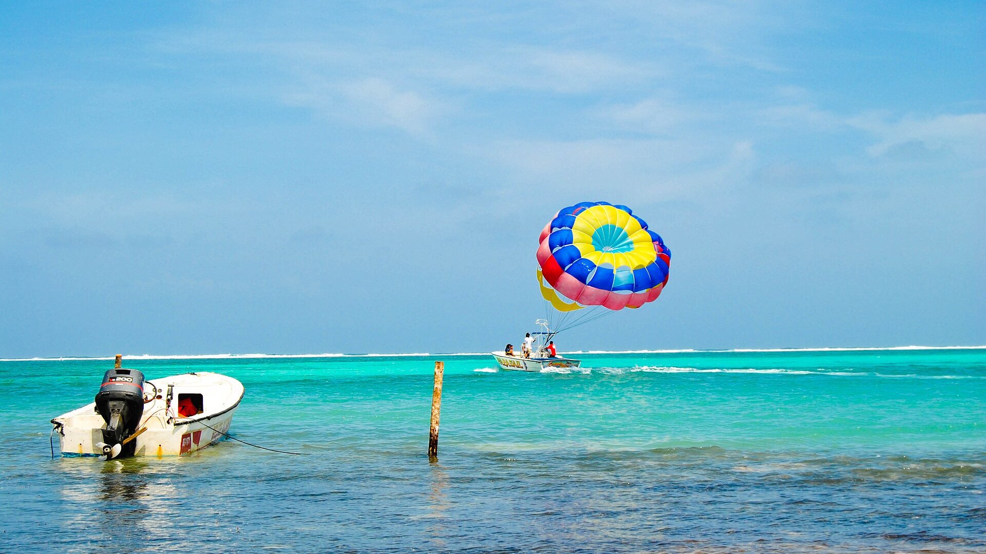 A parasailing boat and a boat moored in turquoise water inside the Belize Barrier Reef off Ambergris Caye