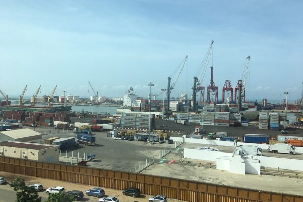 Container cranes, stacked shipping containers and trucks at the Port of Cotonou, Benin, seen from a building overlooking the quay