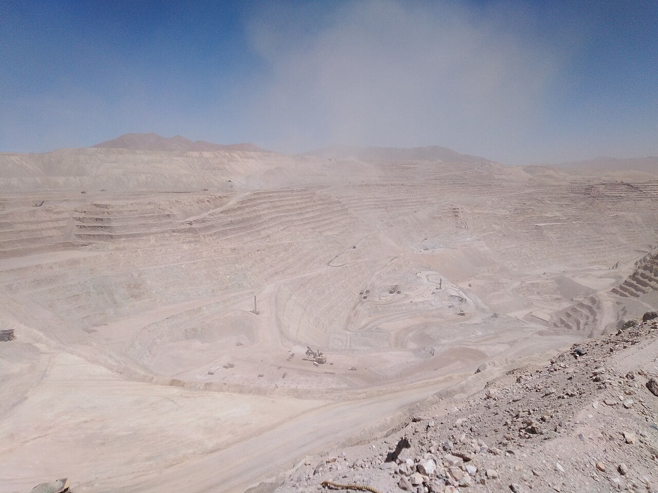 Terraced walls of the Radomiro Tomic open-pit copper mine in Chile's Antofagasta Region under a hazy blue sky