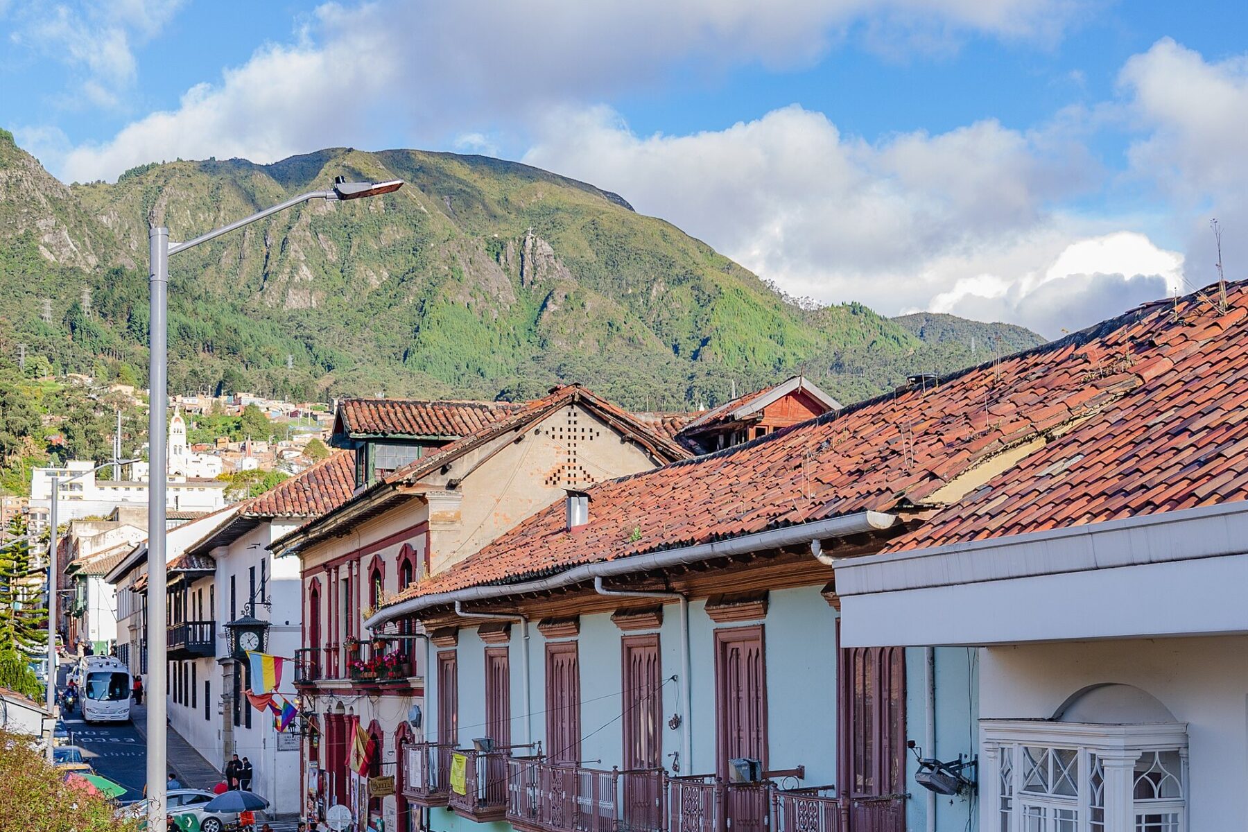 Tiled roofs and balconied colonial houses in La Candelaria, Bogotá, with green Andean hills behind