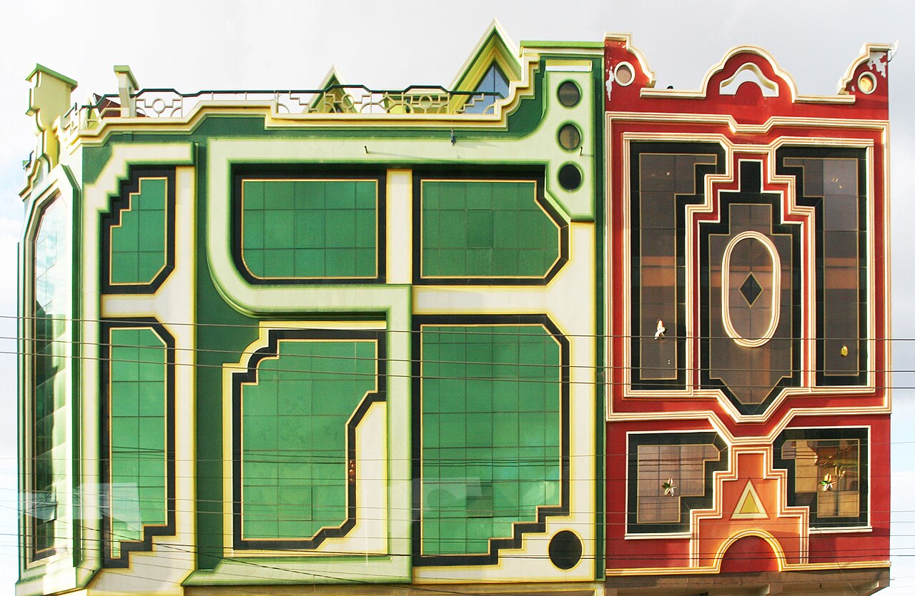 Two neighbouring cholet buildings in El Alto with green glass and bright red facades in Andean geometric patterns