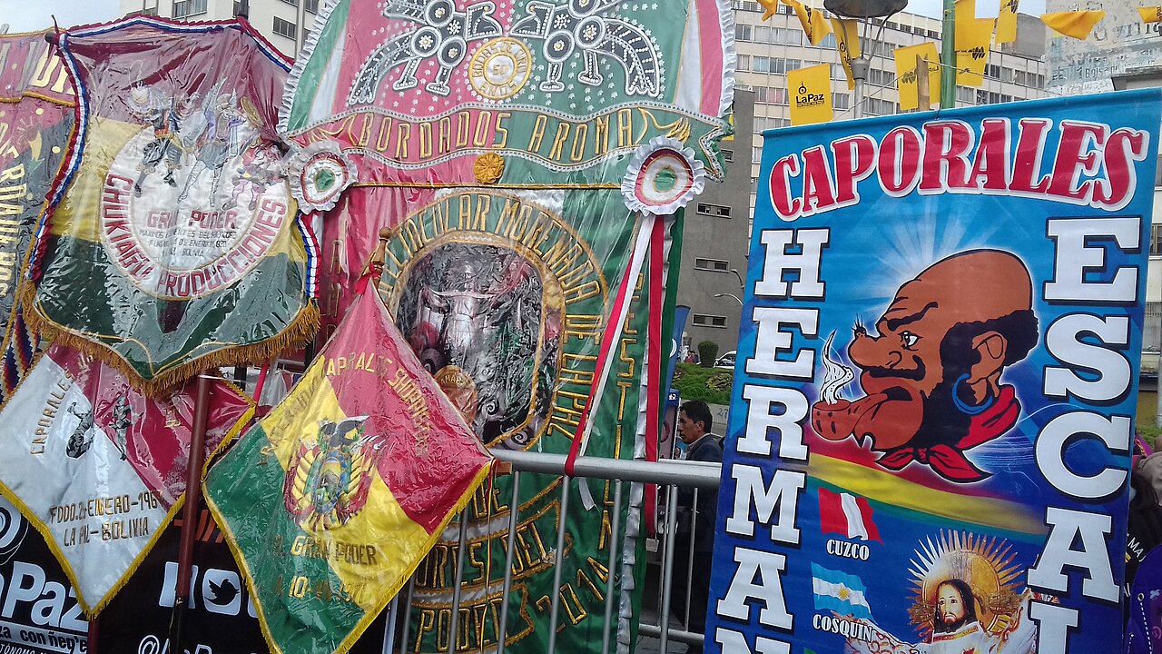 Embroidered banners of dance fraternities for the Gran Poder festival, including a Caporales poster, on a street in La Paz