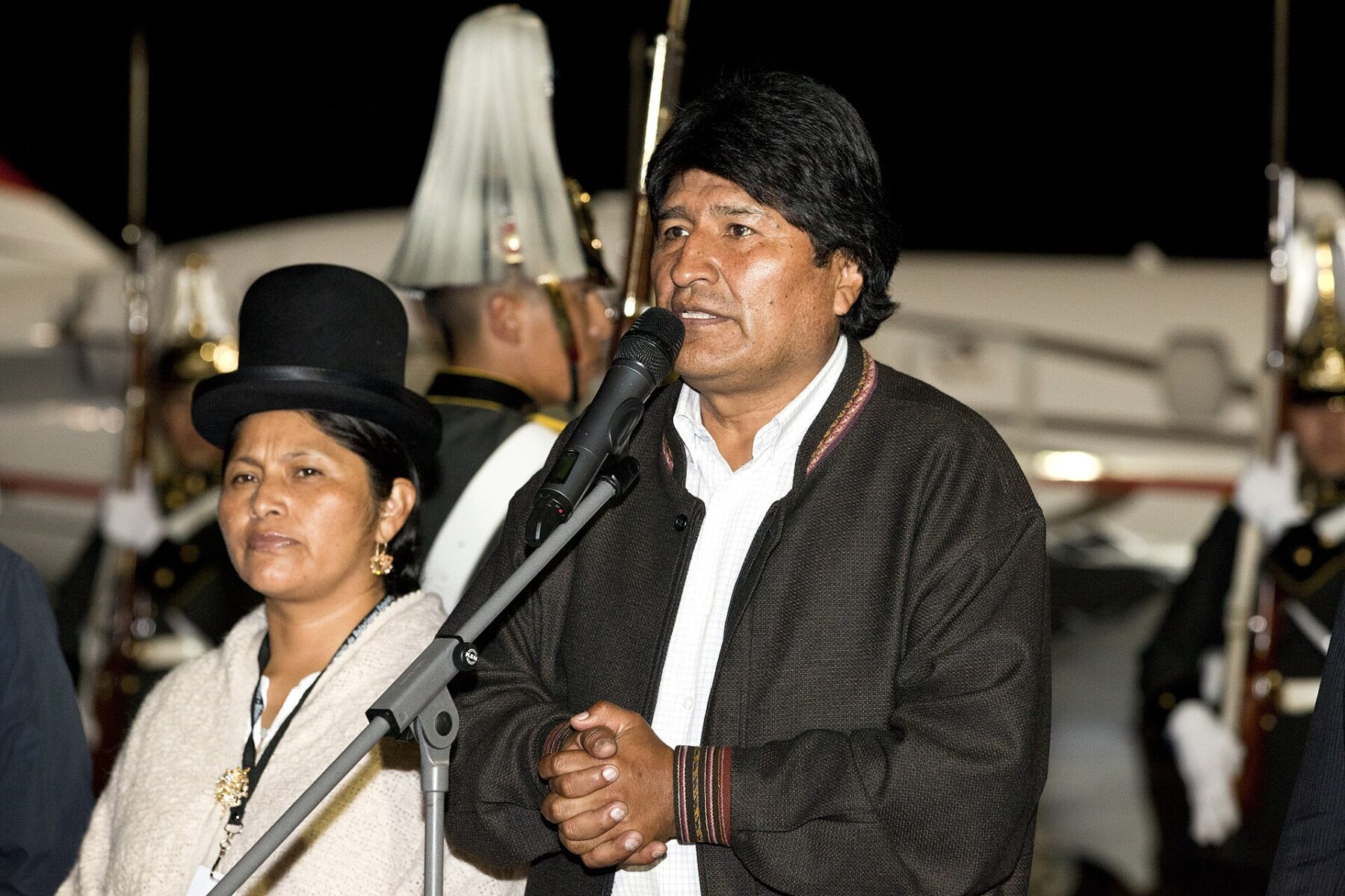 Evo Morales speaks at a microphone at an airport arrival ceremony in Quito