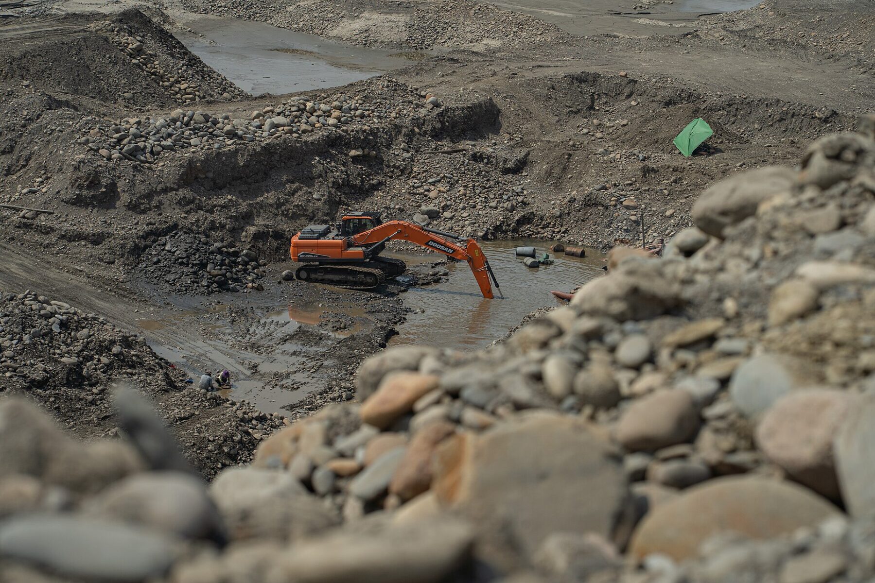 An excavator digs a flooded pit in the bed of the Mapiri River in Bolivia, where small miners work for gold