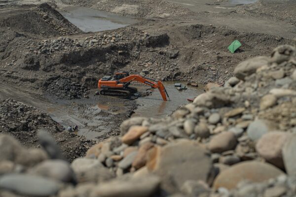 An excavator digs a flooded pit in the bed of the Mapiri River in Bolivia, where small miners work for gold