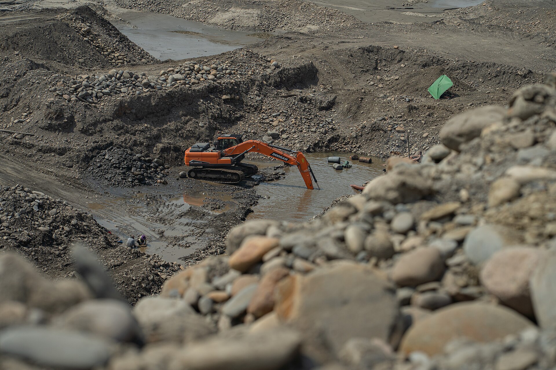 An excavator digs a flooded pit in the bed of the Mapiri River in Bolivia, where small miners work for gold