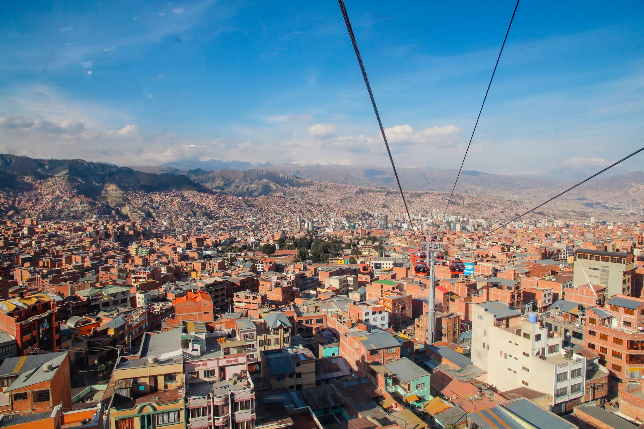 Aerial view over the red-brick houses of La Paz, Bolivia, from a cable car, with mountains in the distance
