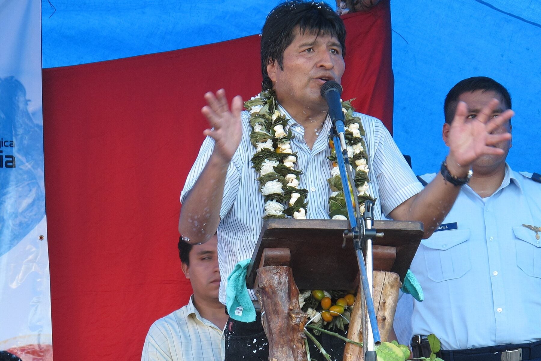 Evo Morales speaking at a lectern wearing a garland during an event in the Chapare, Bolivia