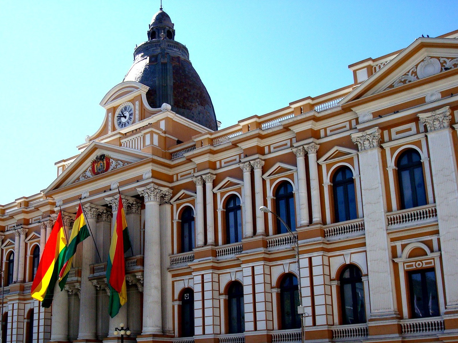 The Legislative Palace in La Paz, Bolivia, with its clock and dome and three flags at the entrance