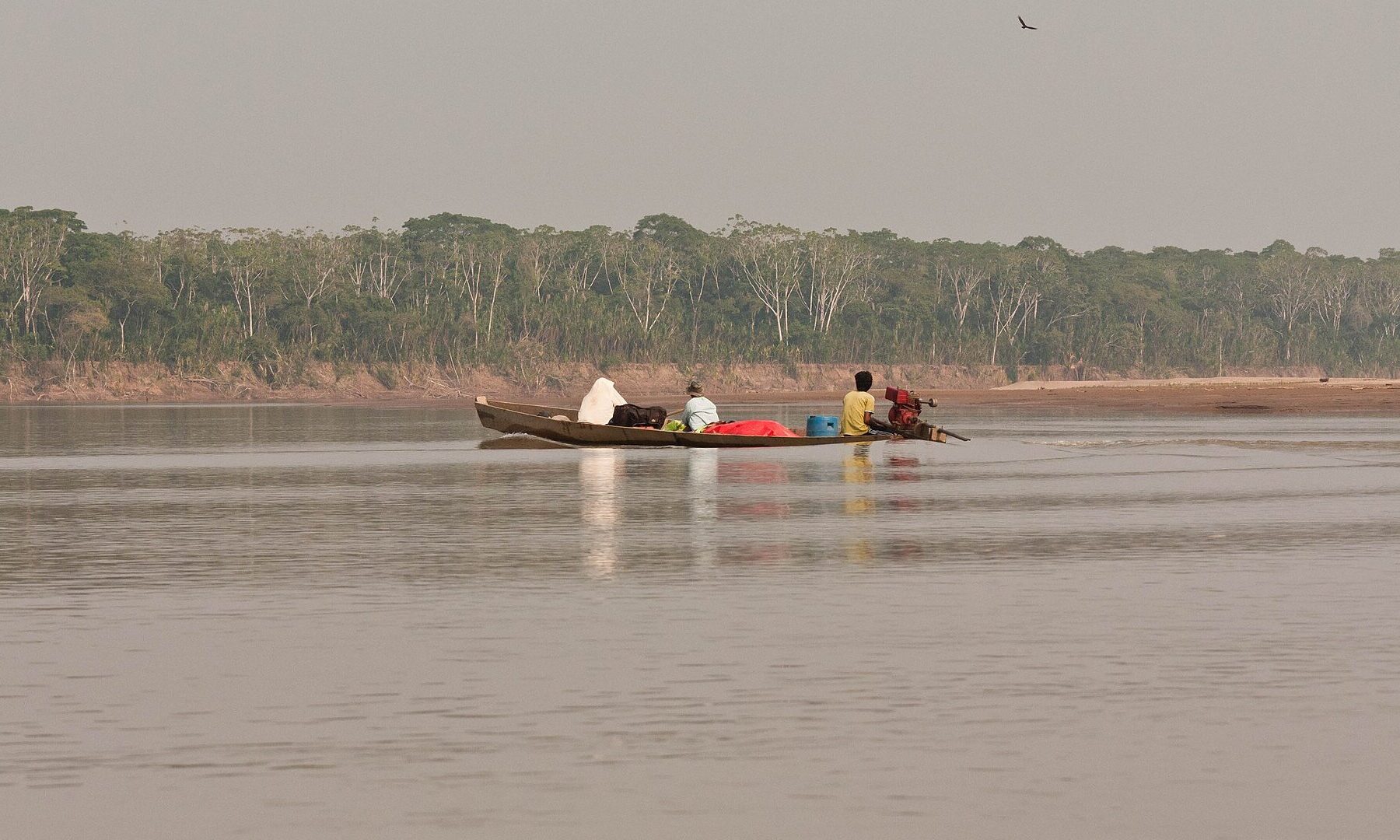 Bolivia illegal mining: a wooden boat with passengers crossing the Beni river near Rurrenabaque in the Bolivian Amazon
