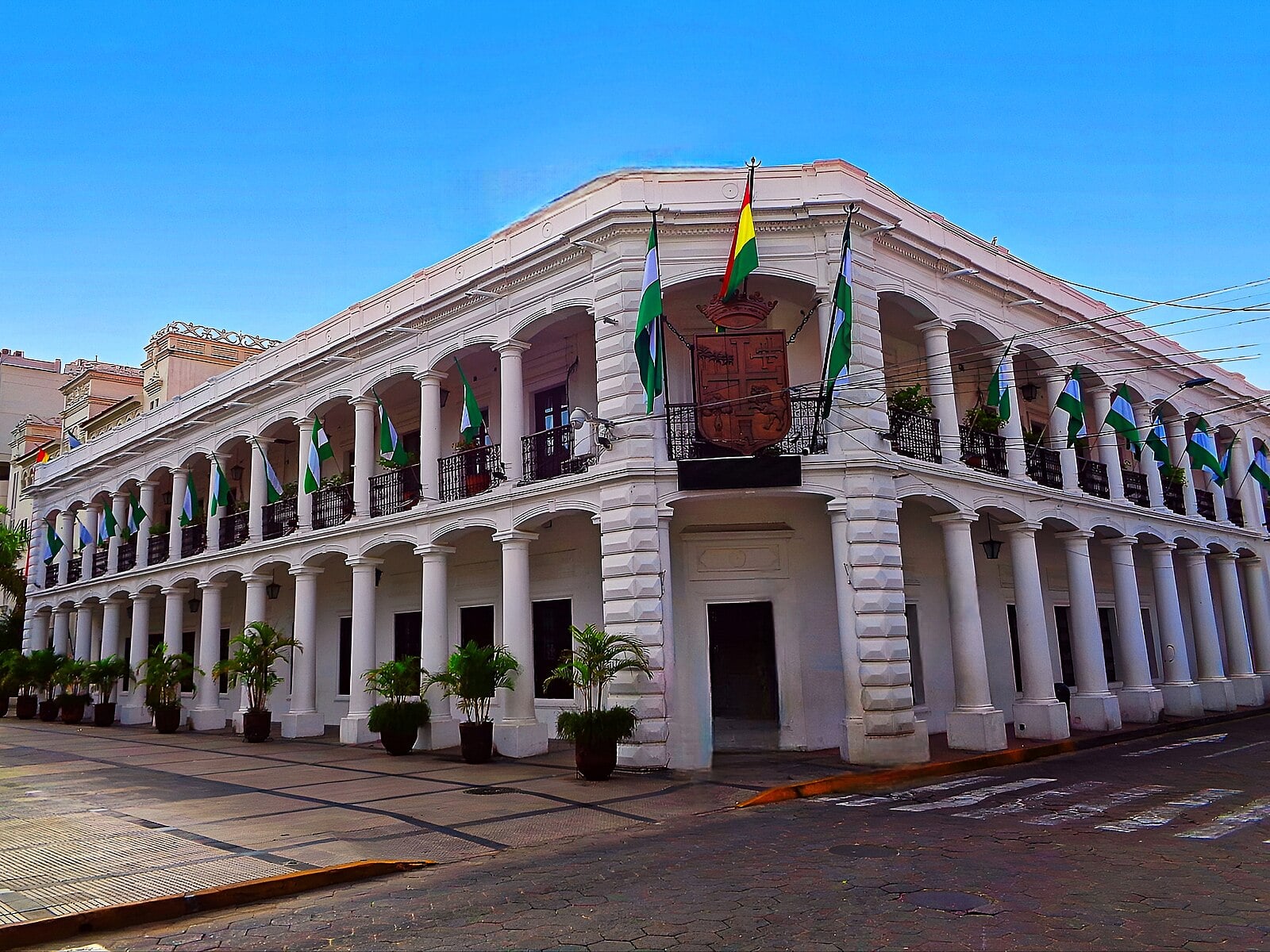 The white colonial municipal building (Alcaldía) in central Santa Cruz de la Sierra, Bolivia, with Bolivian and Santa Cruz flags on its balconies