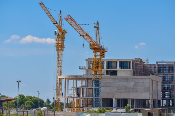 Two yellow tower cranes beside a concrete building under construction in Gaborone, Botswana, under a blue sky