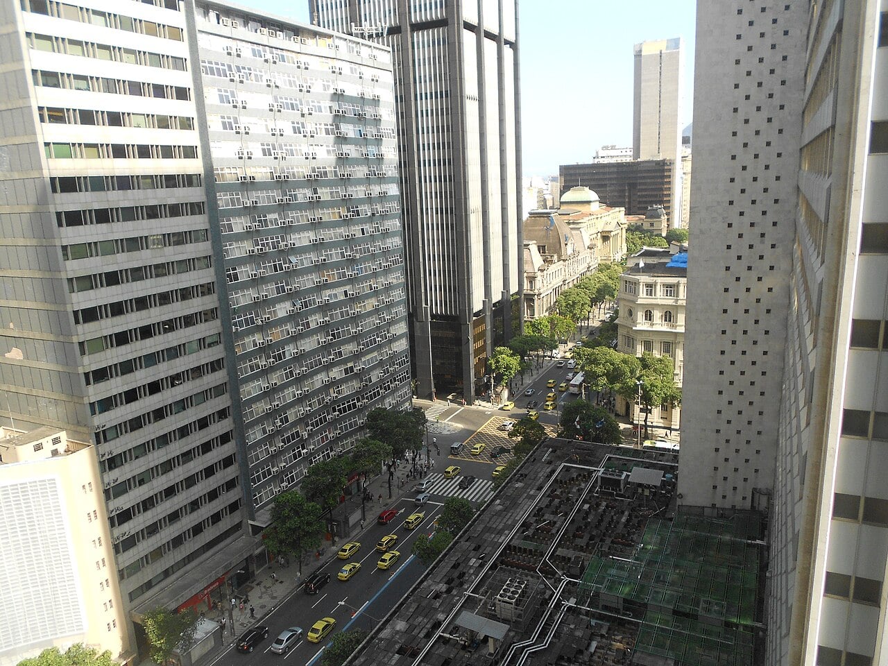 View down Avenida Rio Branco in central Rio de Janeiro, with office towers, a historic domed building and yellow taxis on the street