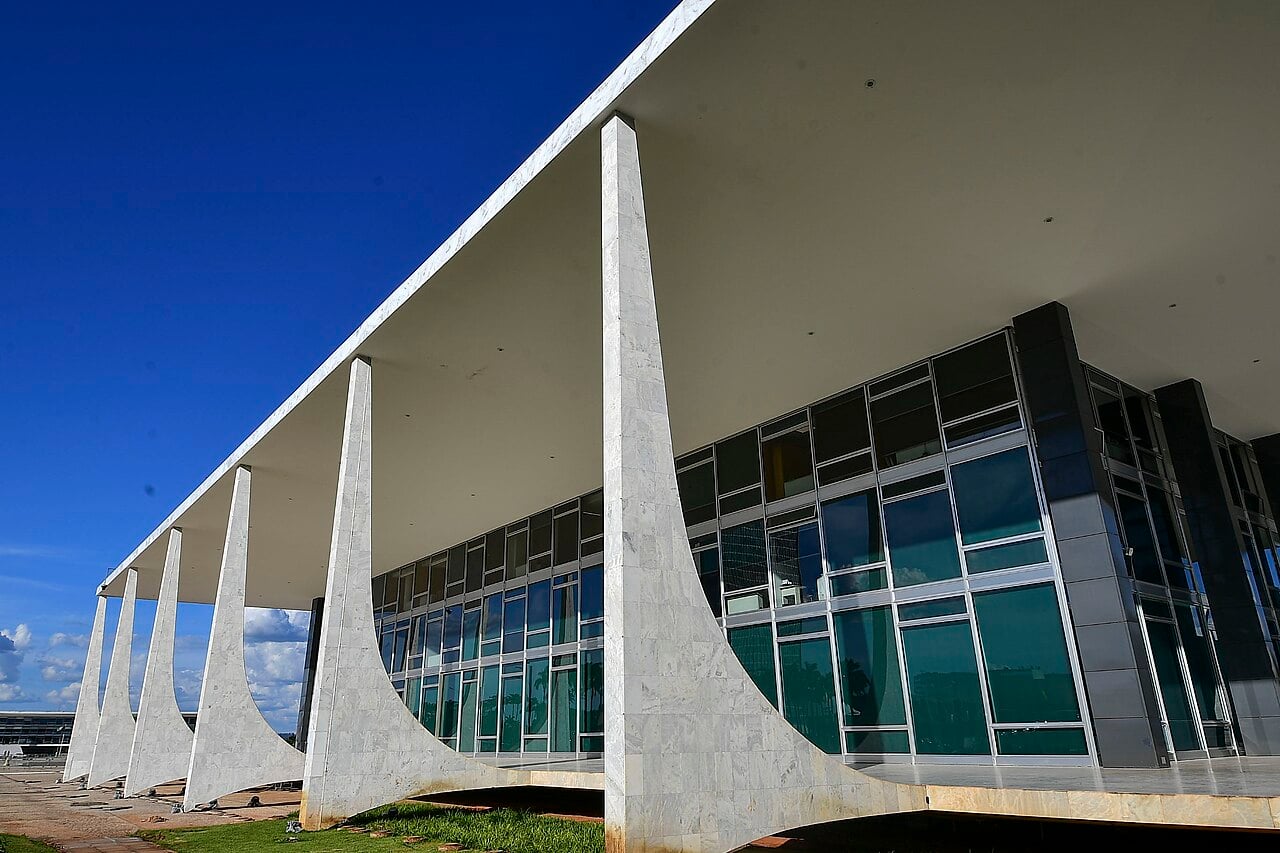 The Supreme Federal Court building in Brasília, with curved white marble columns and a glass facade under a blue sky