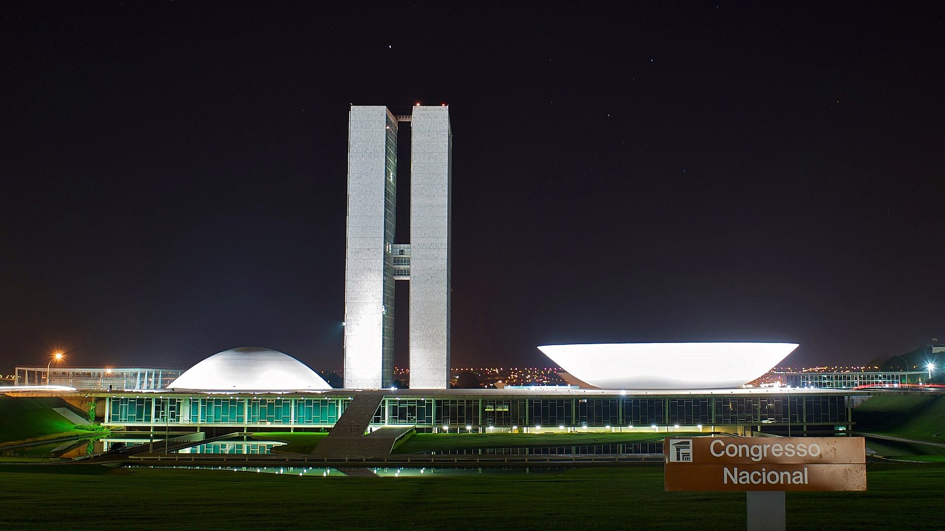 Brazil's National Congress in Brasília at night, with the twin office towers and the two domes, beside a Congresso Nacional sign