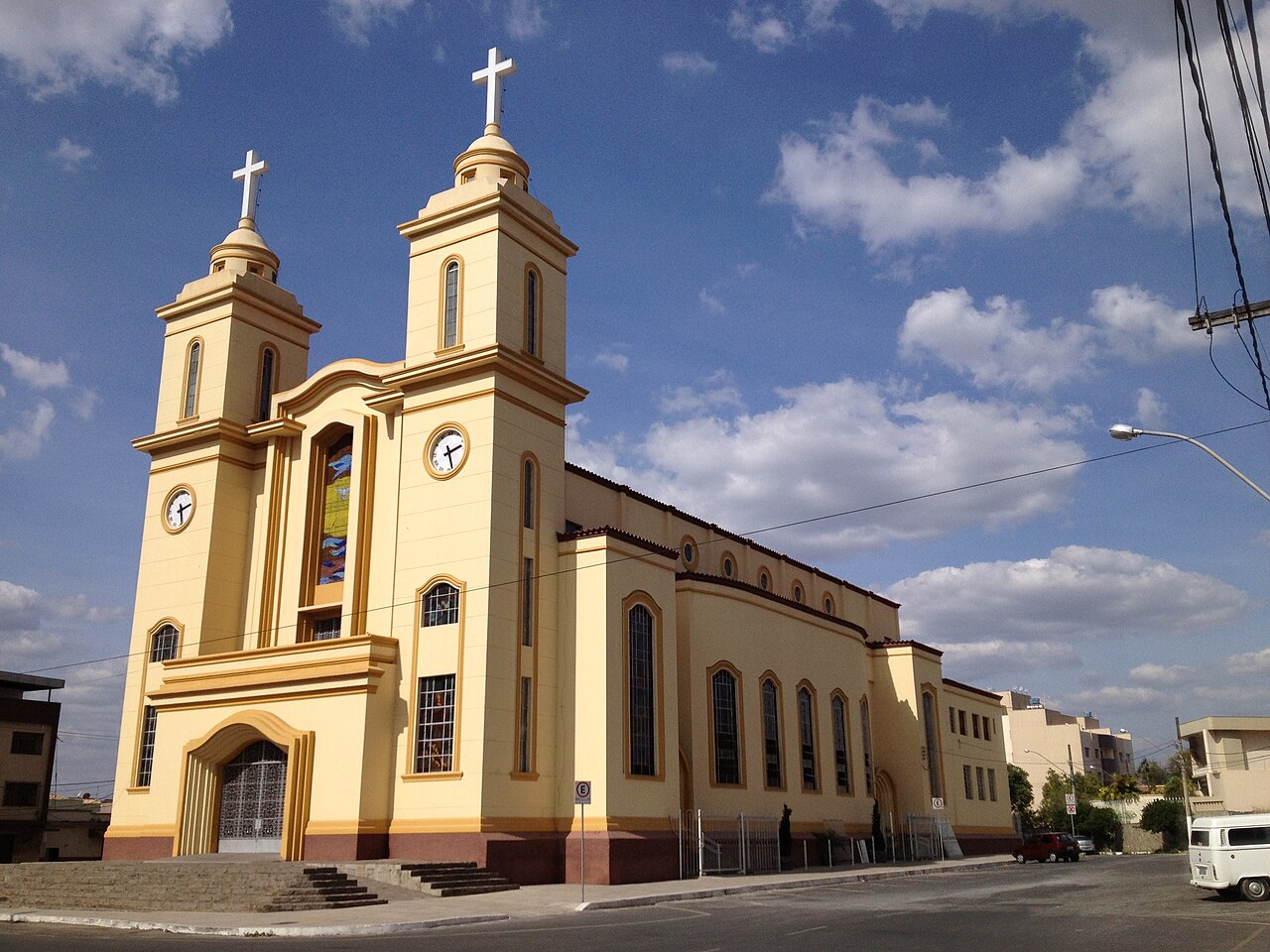 Yellow twin-towered cathedral of Divinópolis in Minas Gerais seen from the street corner under a blue sky