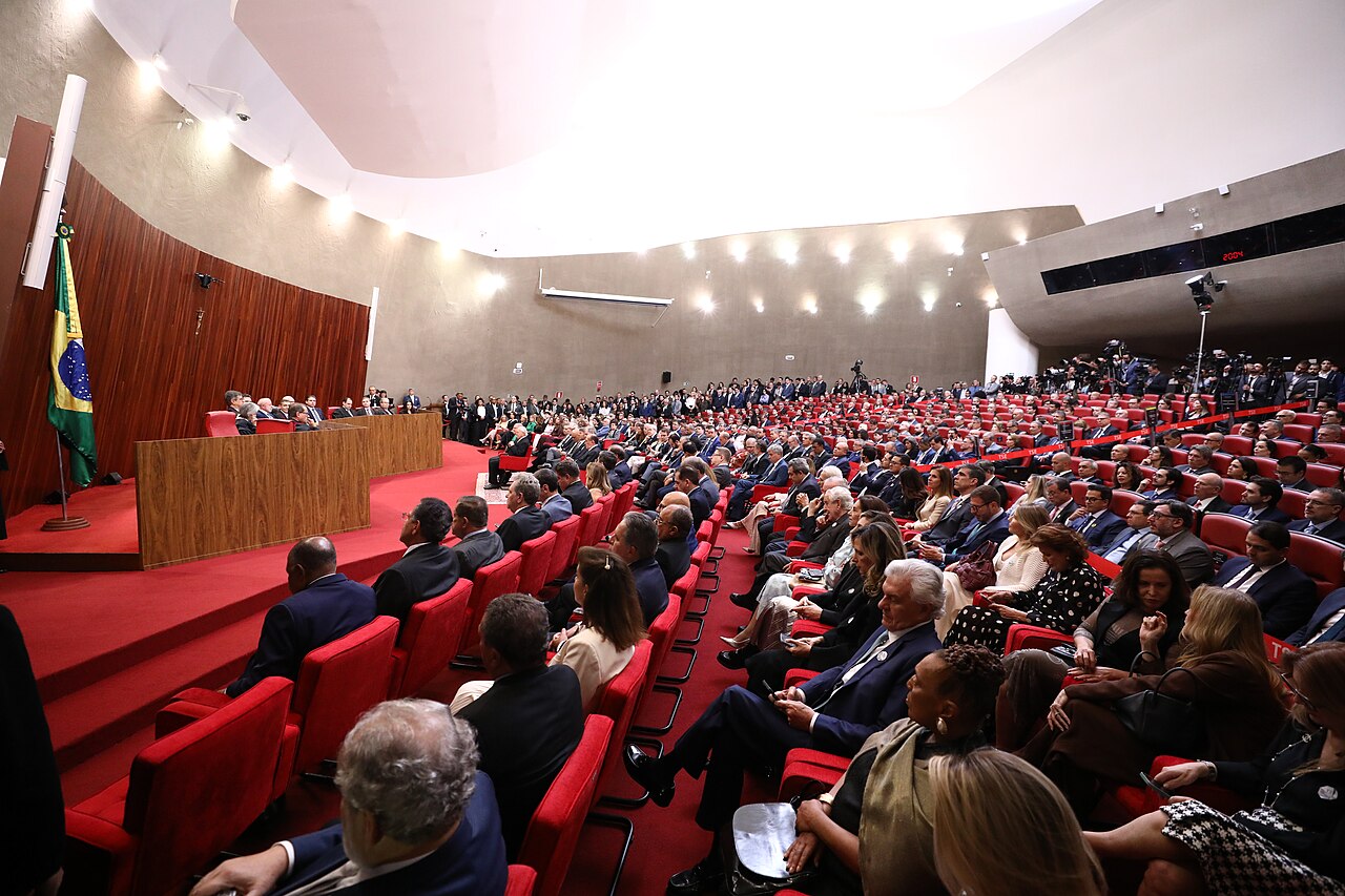A packed chamber with red seats faces the judges' bench and a Brazilian flag inside Brazil's Superior Electoral Court