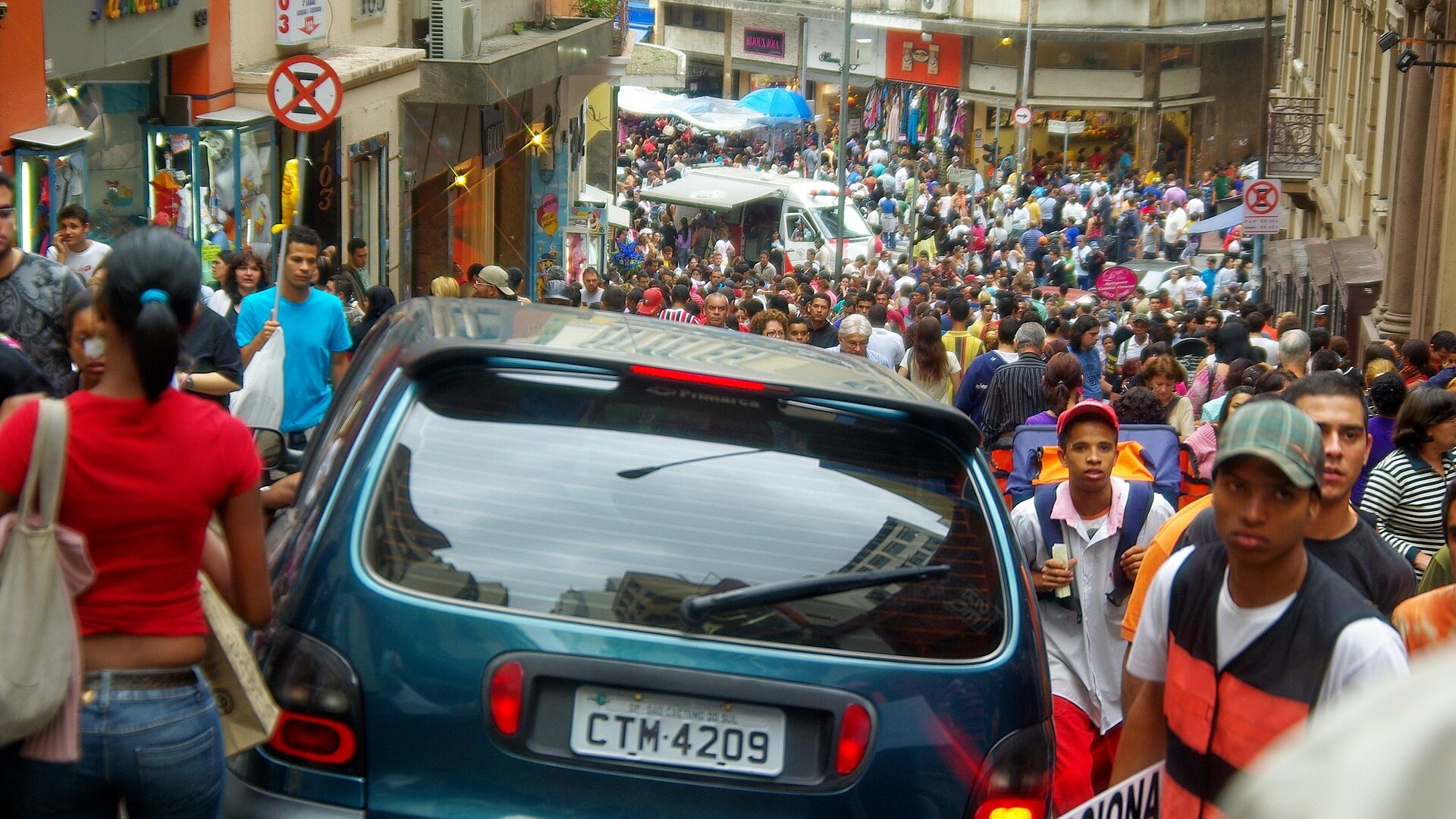 Crowds of shoppers fill Rua 25 de Março, a steep and busy shopping street in central São Paulo