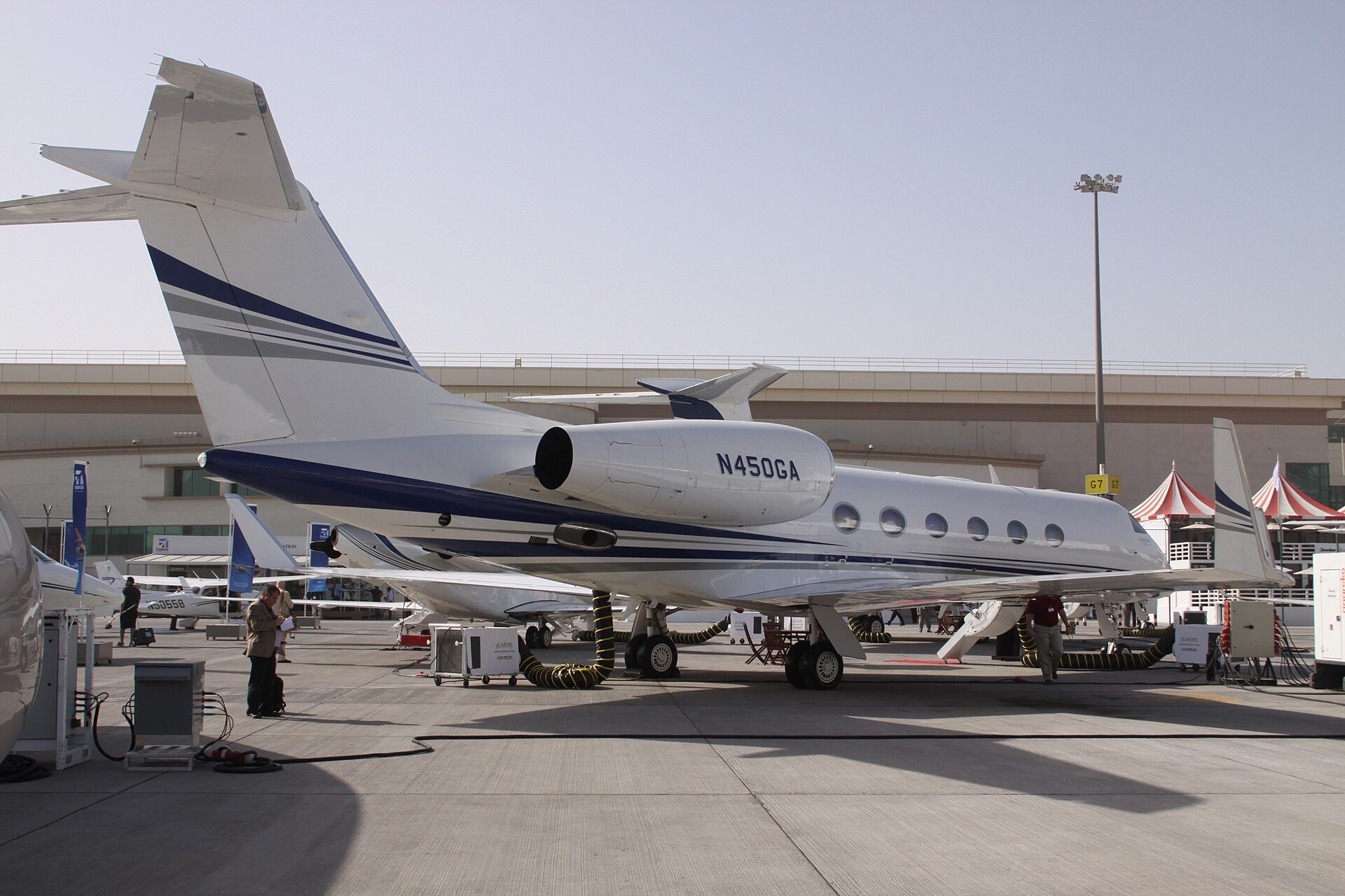 A white and blue Gulfstream G450 business jet parked on an airport apron with its registration N450GA on the engine