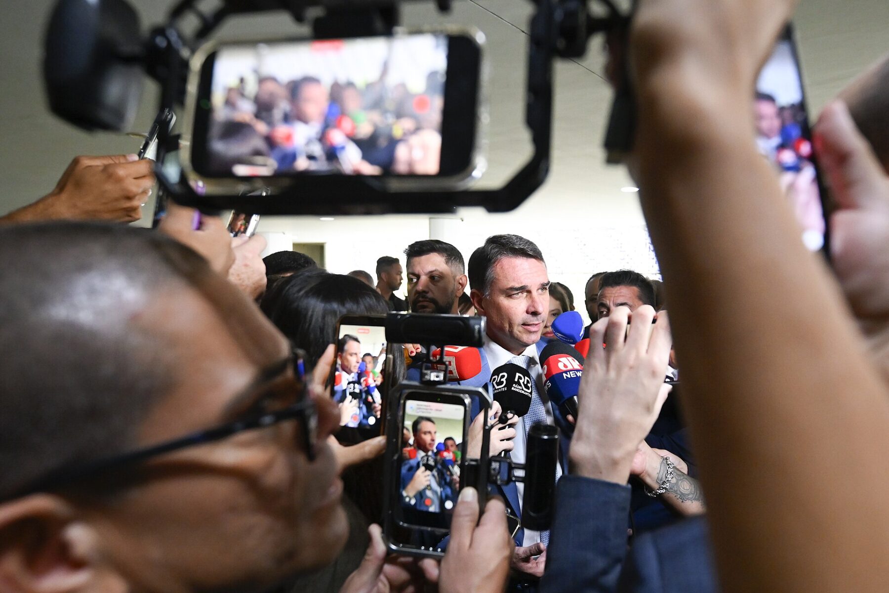 Senator Flávio Bolsonaro speaks to reporters surrounded by microphones and phones at Brazil’s Senate in Brasília