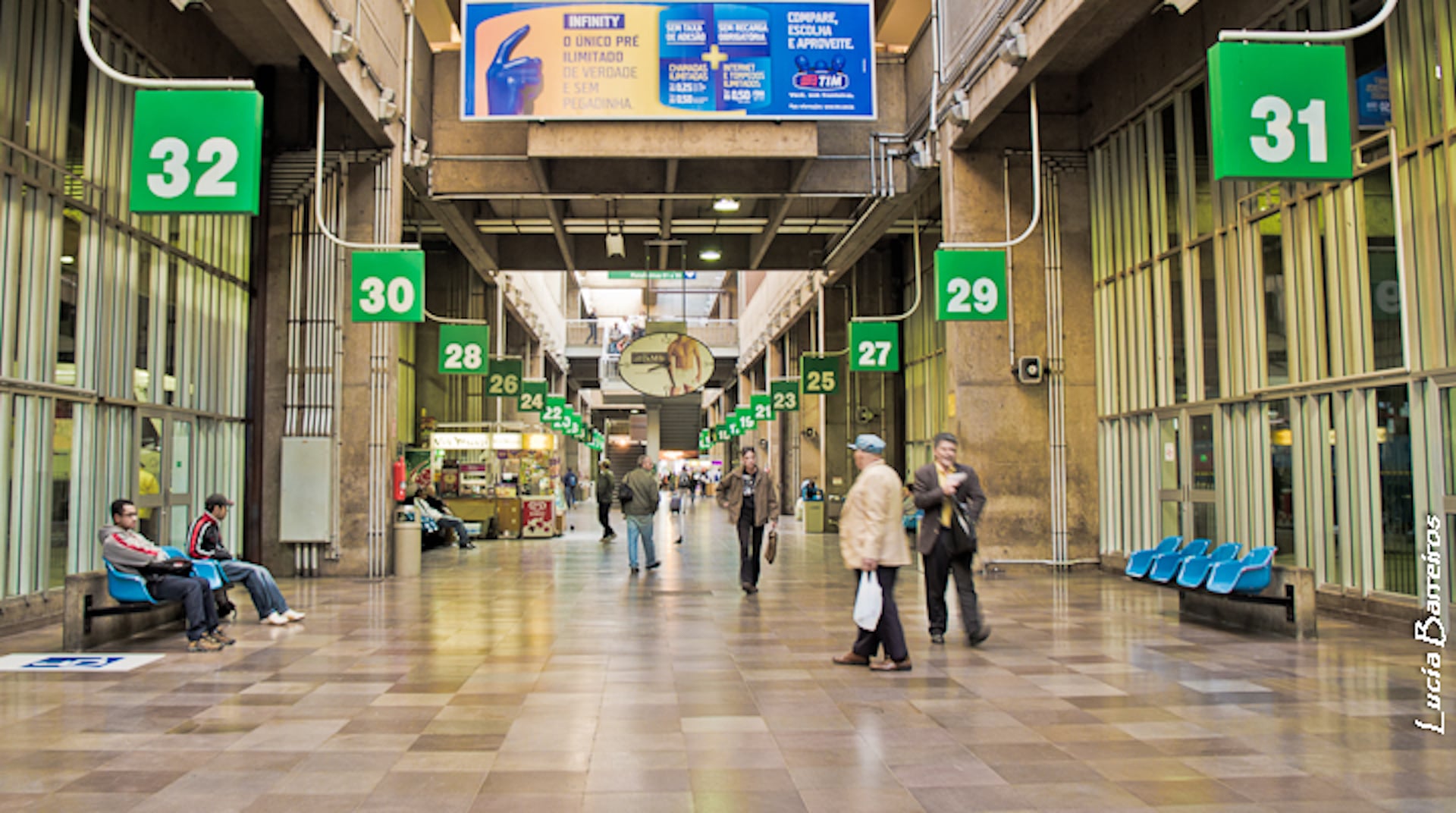 Passengers walk through the concourse of the Tietê bus terminal in São Paulo past numbered boarding gates