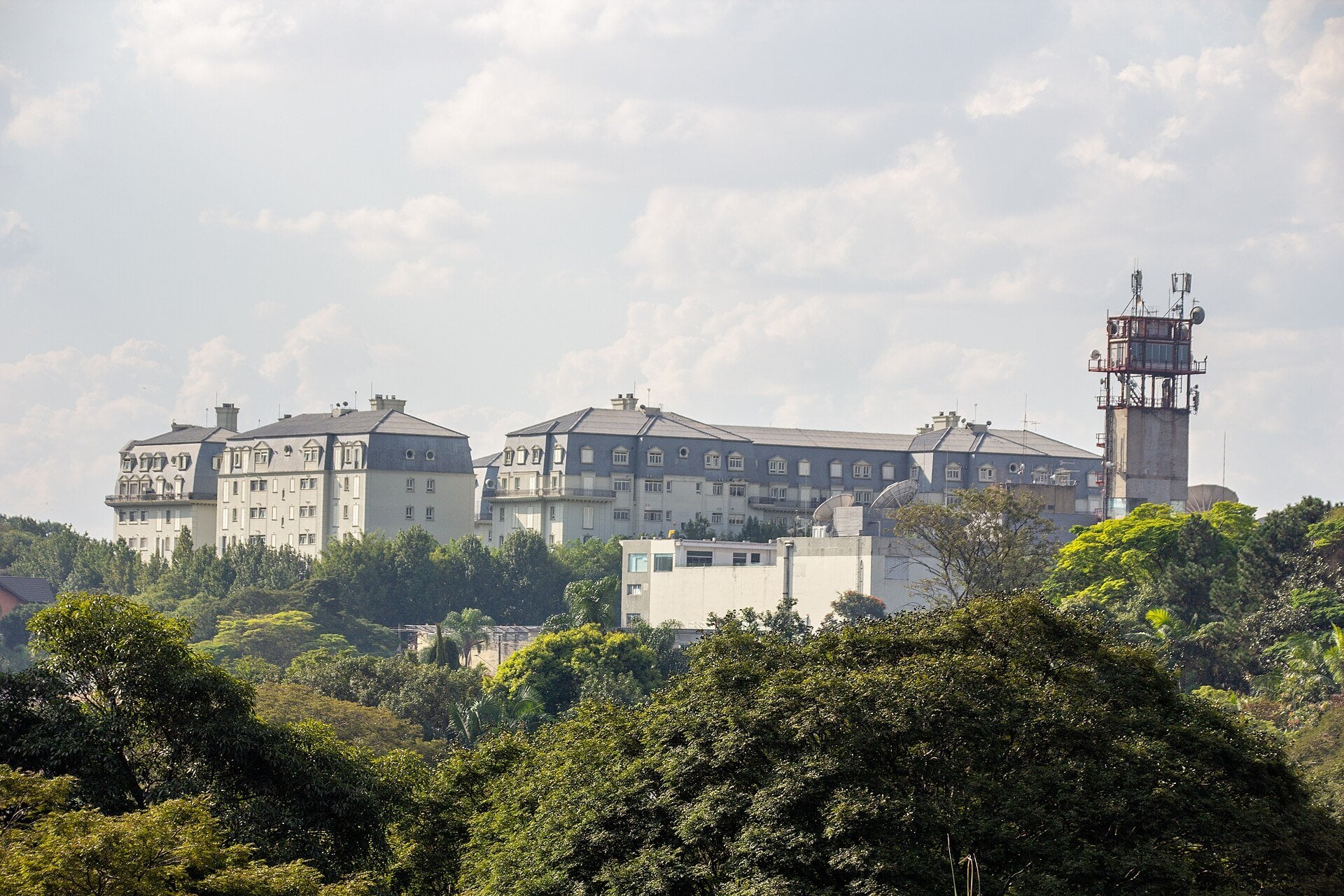 Palácio dos Bandeirantes, the São Paulo governor's seat, a white and grey French-style building on a wooded hill under a cloudy sky