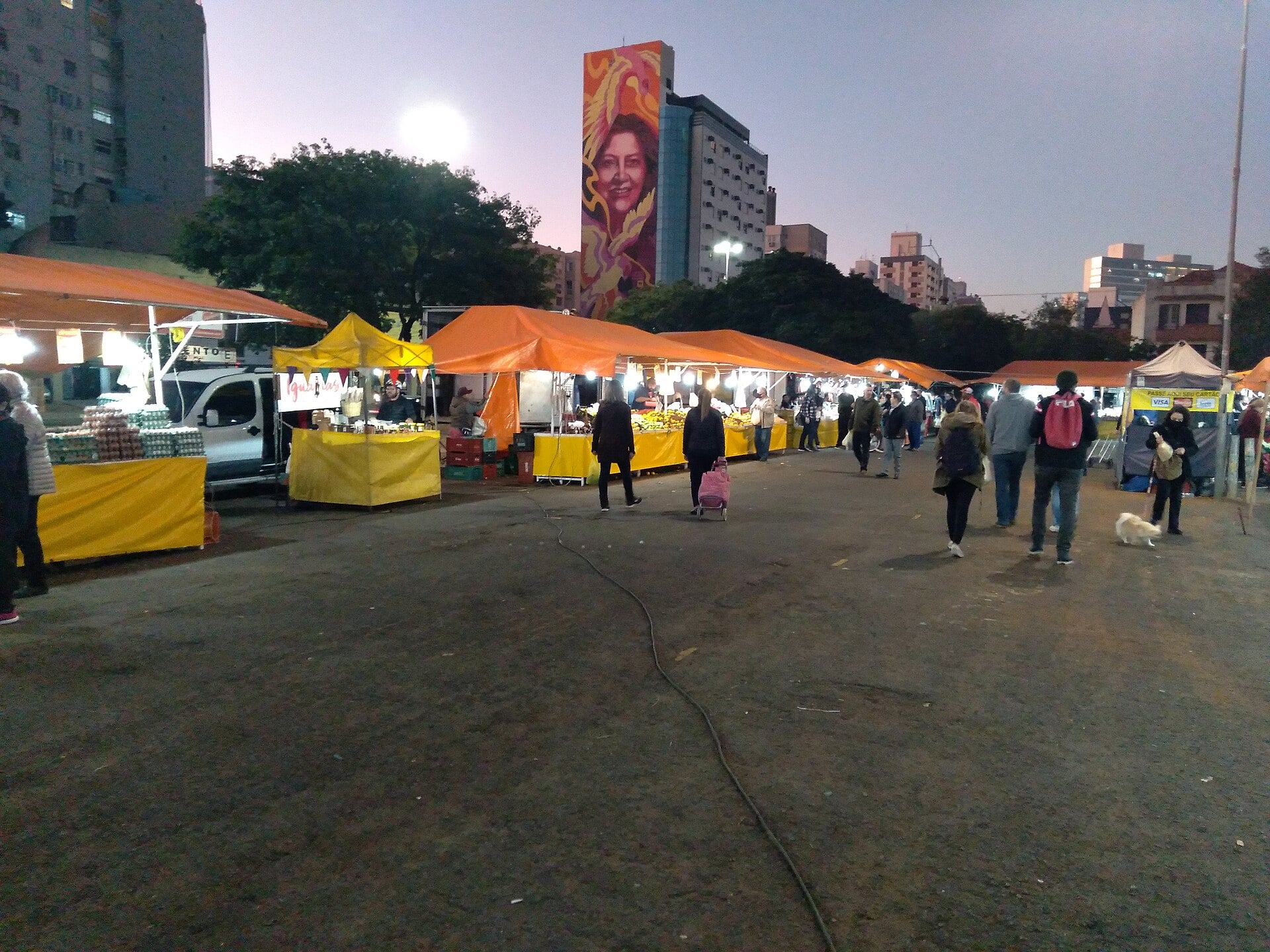 Orange and yellow vendor stalls at an evening street market at Largo da Epatur in Porto Alegre, Brazil