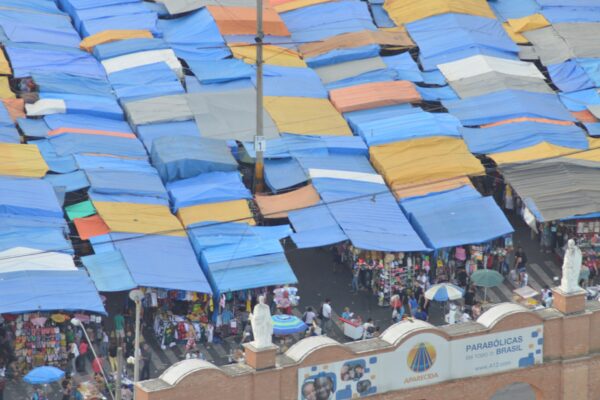 Rows of blue and yellow covered vendor stalls at a street market in Aparecida, São Paulo state