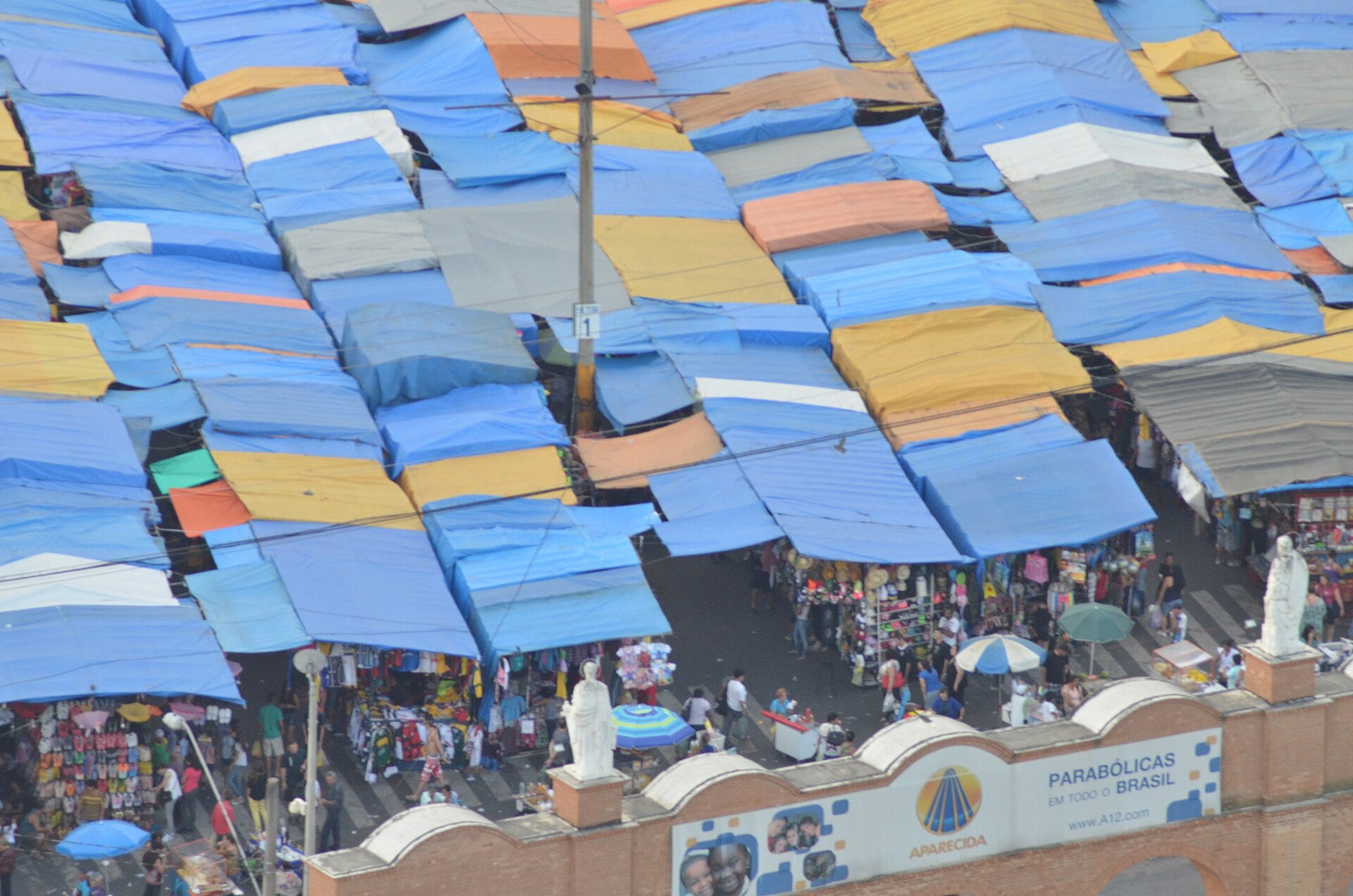Rows of blue and yellow covered vendor stalls at a street market in Aparecida, São Paulo state