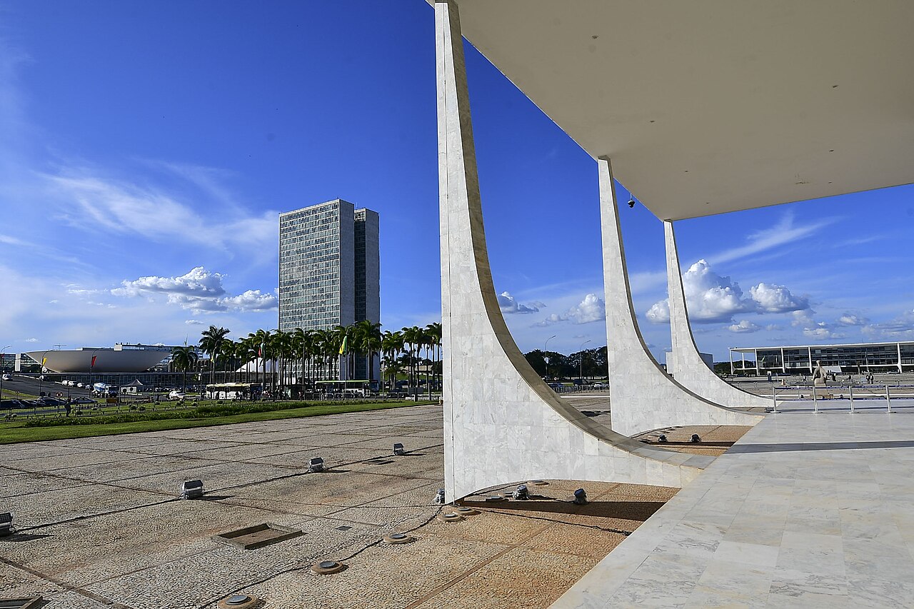 White curved marble columns of Brazil's Supreme Court building in Brasília, with the twin towers of the National Congress behind