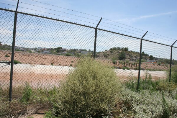 A chain-link fence topped with barbed wire on the US side of the border at El Paso, Texas, with Ciudad Juárez, Mexico, beyond