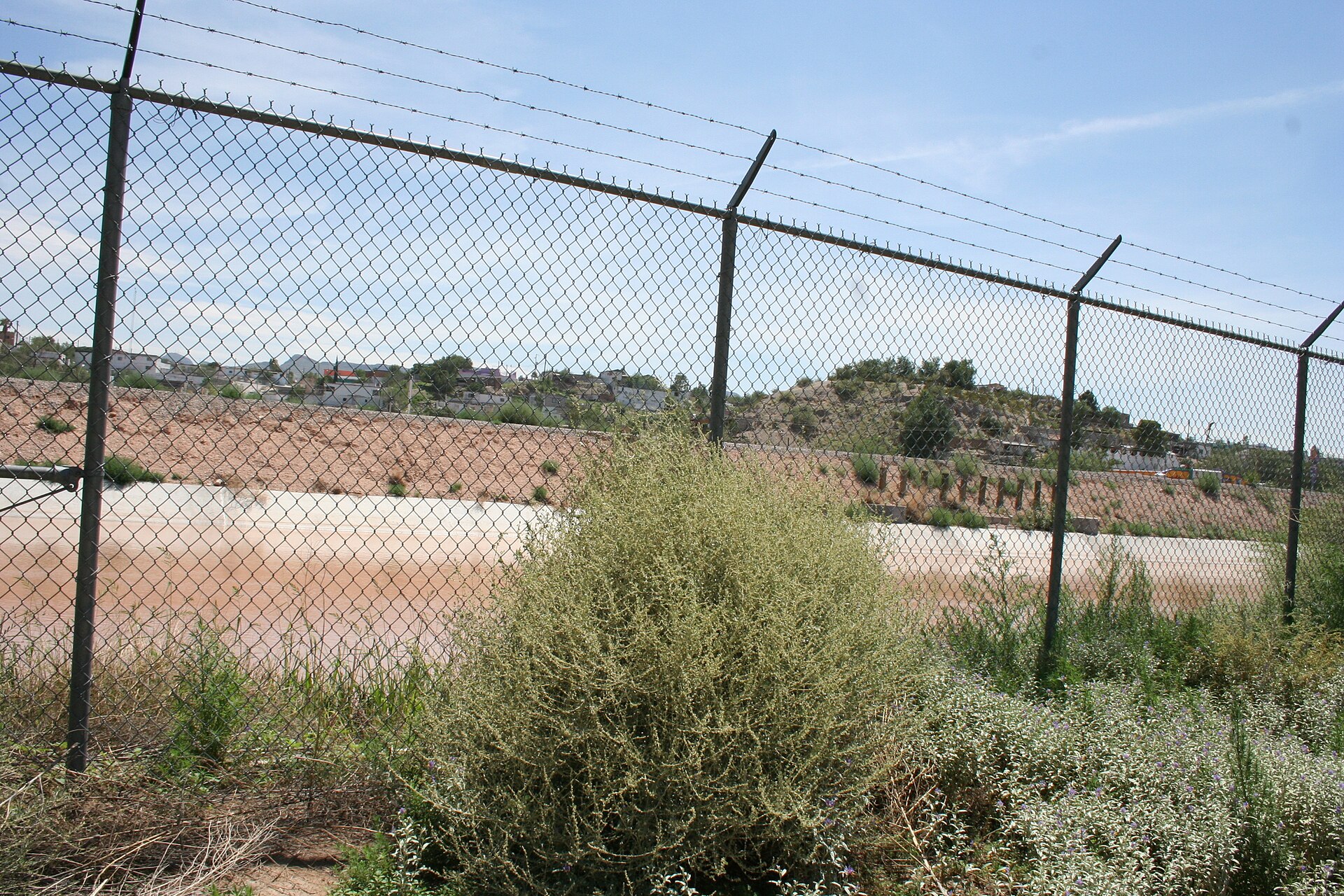 A chain-link fence topped with barbed wire on the US side of the border at El Paso, Texas, with Ciudad Juárez, Mexico, beyond