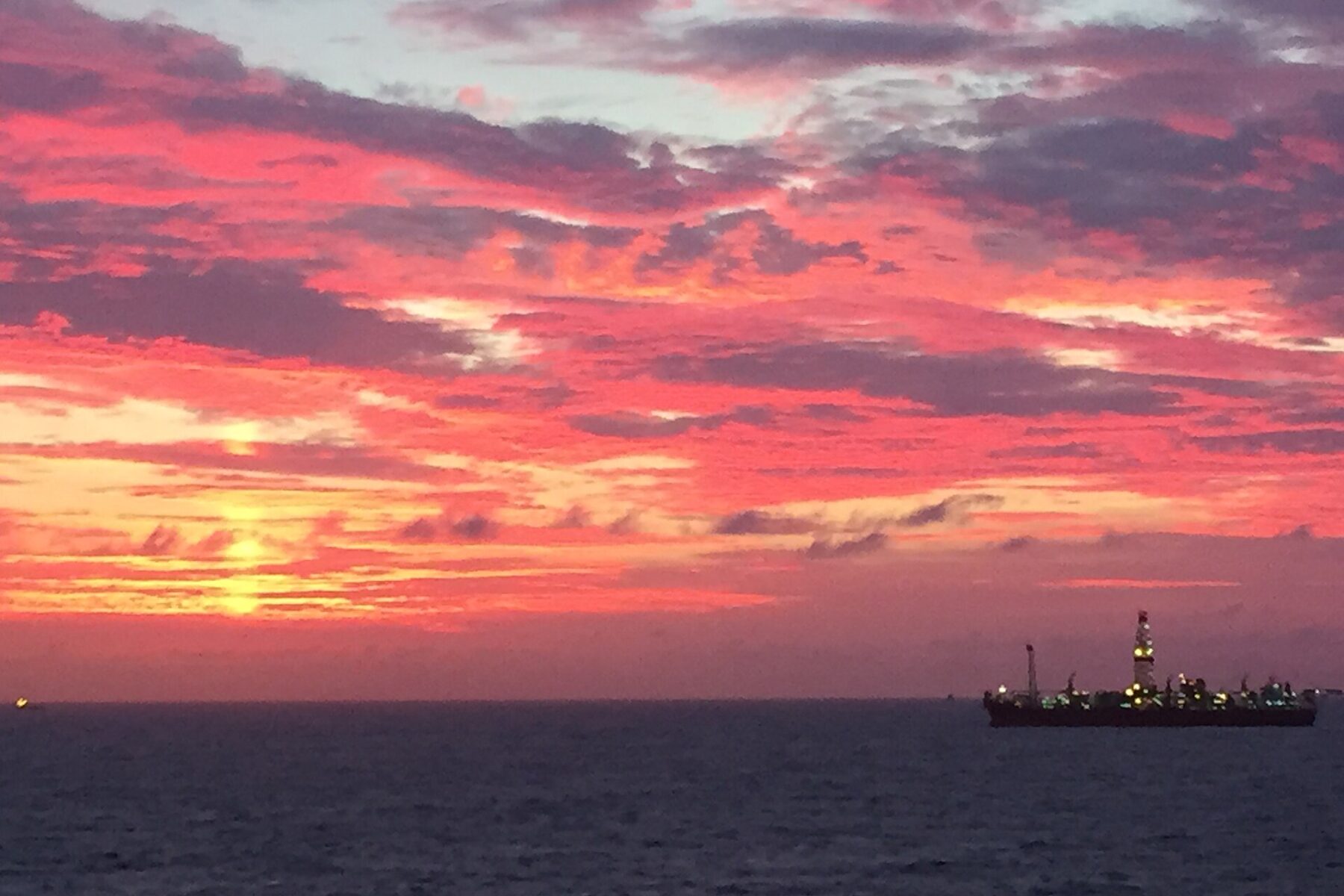Sunrise over the Santos Basin off Brazil with an offshore oil unit lit up on the horizon