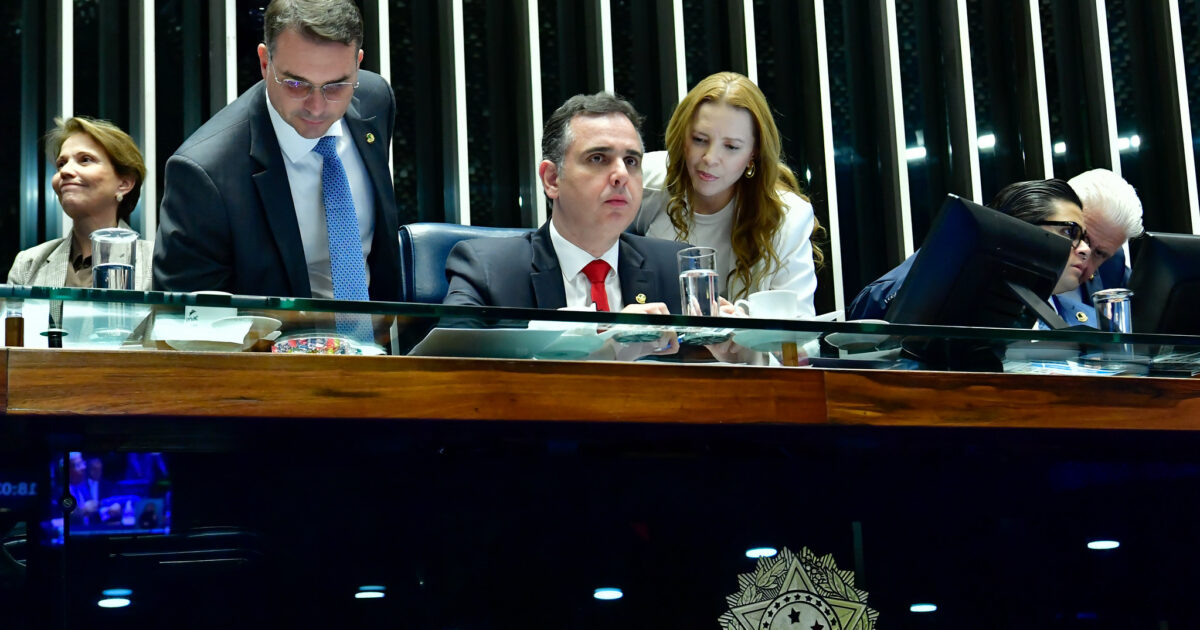 Flávio Bolsonaro standing at the Senate presiding table beside then Senate president Rodrigo Pacheco
