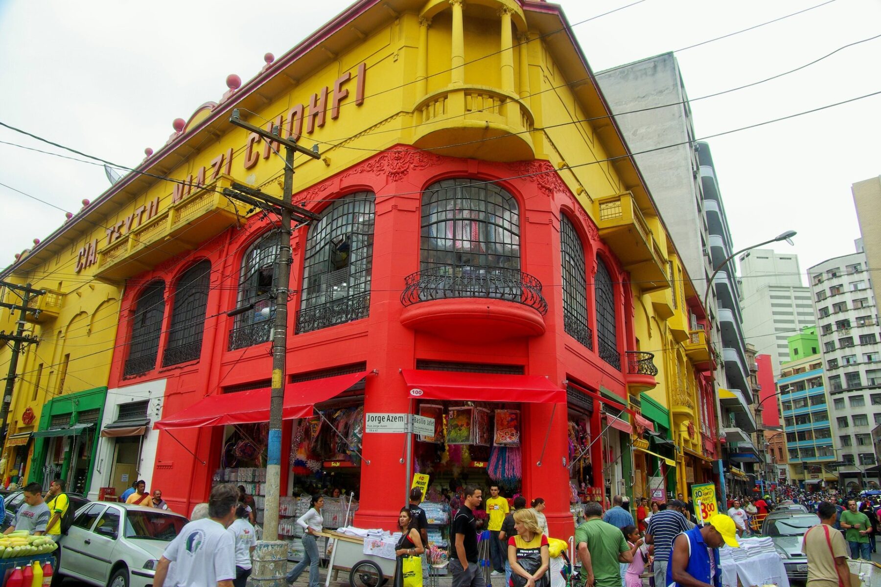 Shoppers outside a red and yellow shop building on Rua 25 de Março in central São Paulo, Brazil