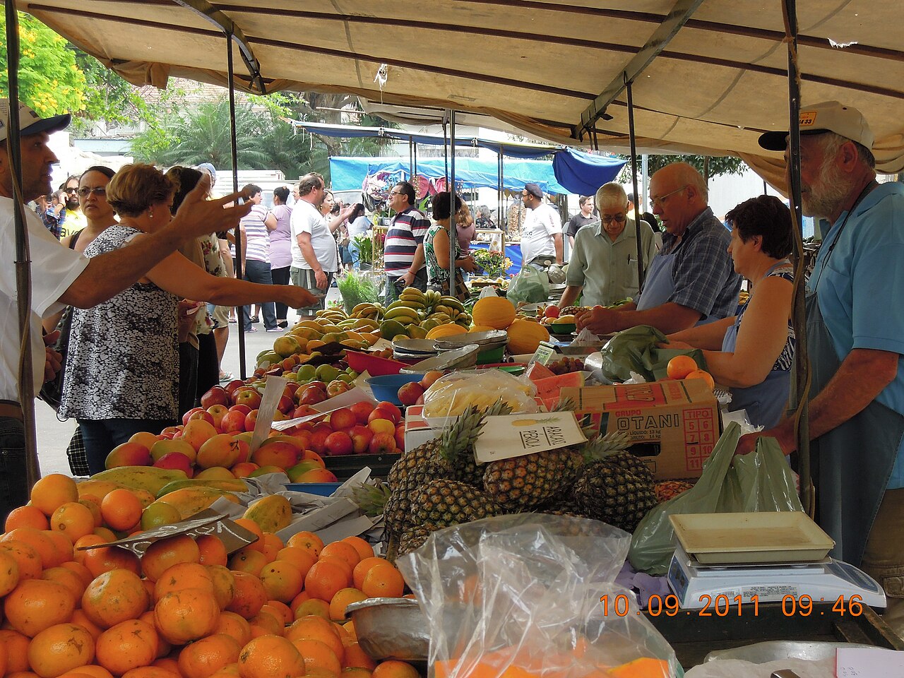 Vendors sell oranges, pineapples and apples under canvas awnings at a Saturday street market in Jaguariúna, São Paulo state