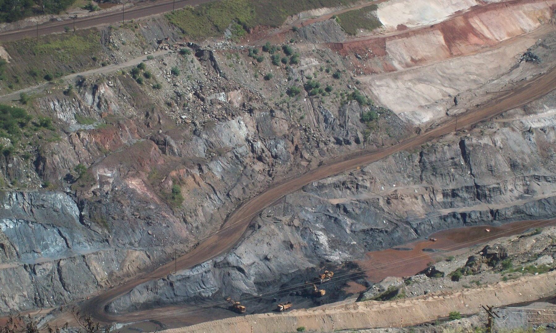 Terraced open-pit iron ore mine with trucks and excavators at the bottom in Itabira, Brazil