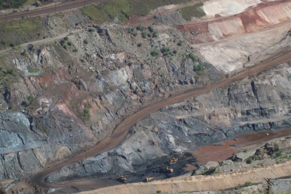 Terraced open-pit iron ore mine with trucks and excavators at the bottom in Itabira, Brazil