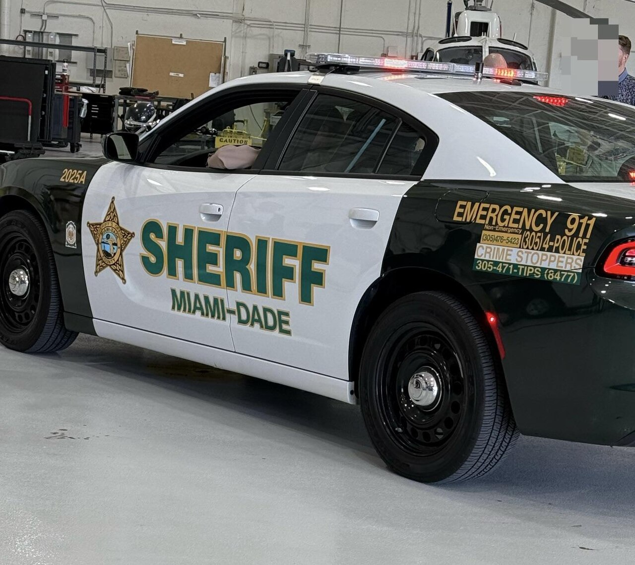 A green and white Miami-Dade Sheriff patrol car parked inside a hangar