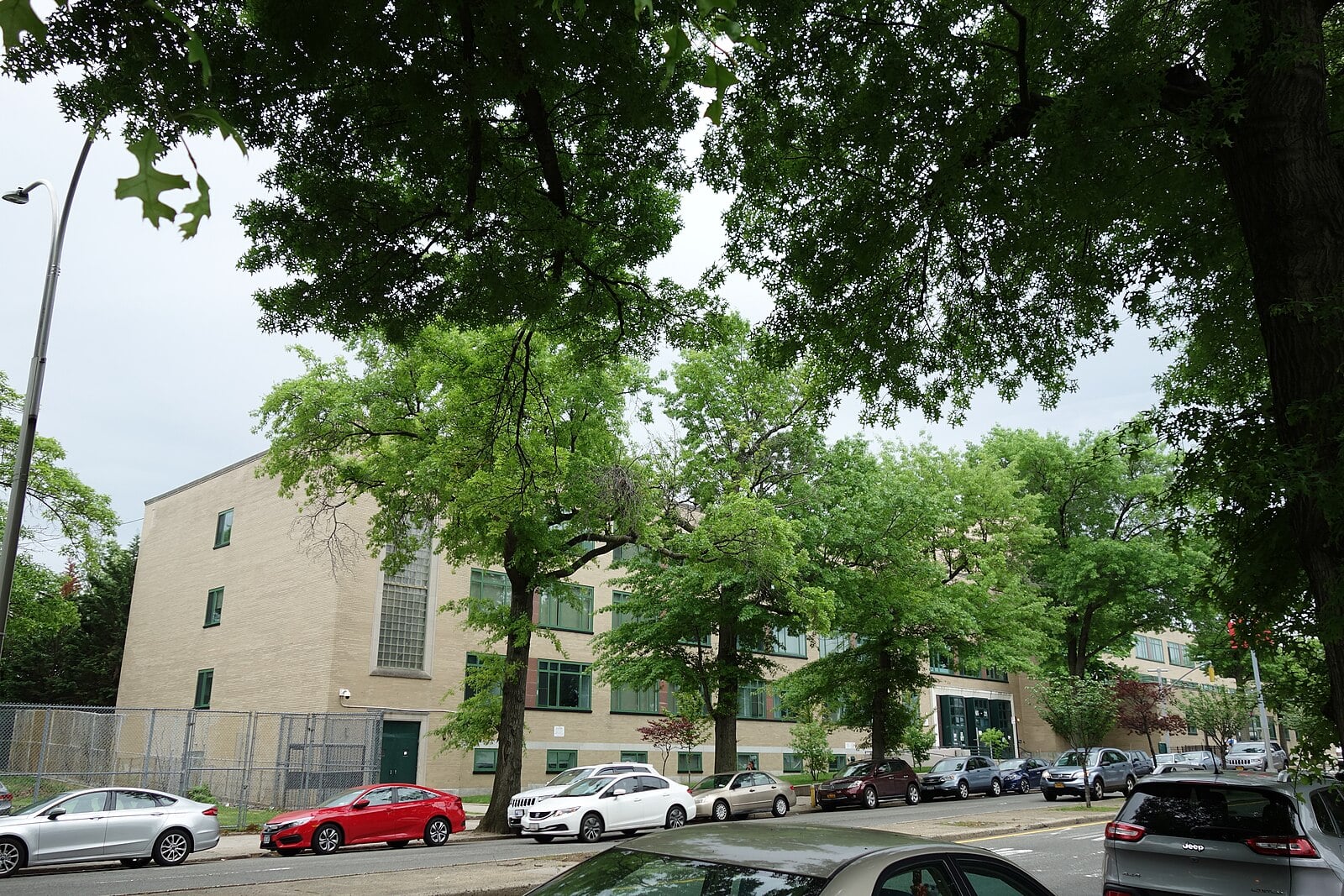 A beige school building on tree-lined Main Street at the west end of the Queens College campus in Flushing, Queens, New York