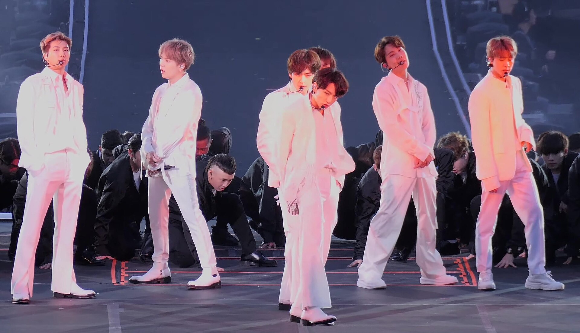 BTS members in white suits performing on stage at MetLife Stadium in 2019