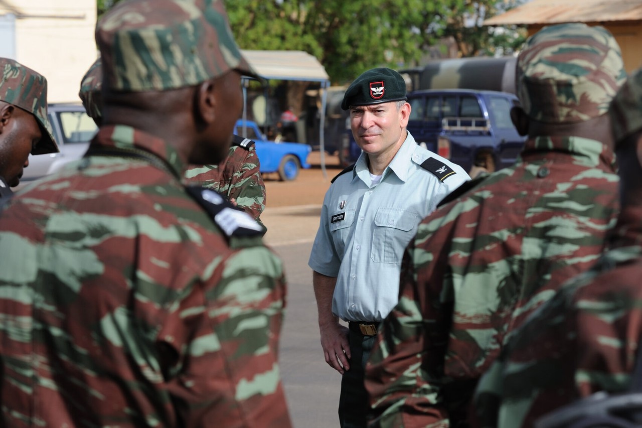 A US Army colonel stands among Burkinabè soldiers in camouflage uniforms during a regional training exercise