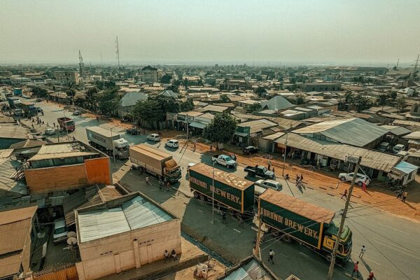 Aerial view of a busy road in Bujumbura, Burundi, with brewery lorries, shops with corrugated roofs and pedestrians