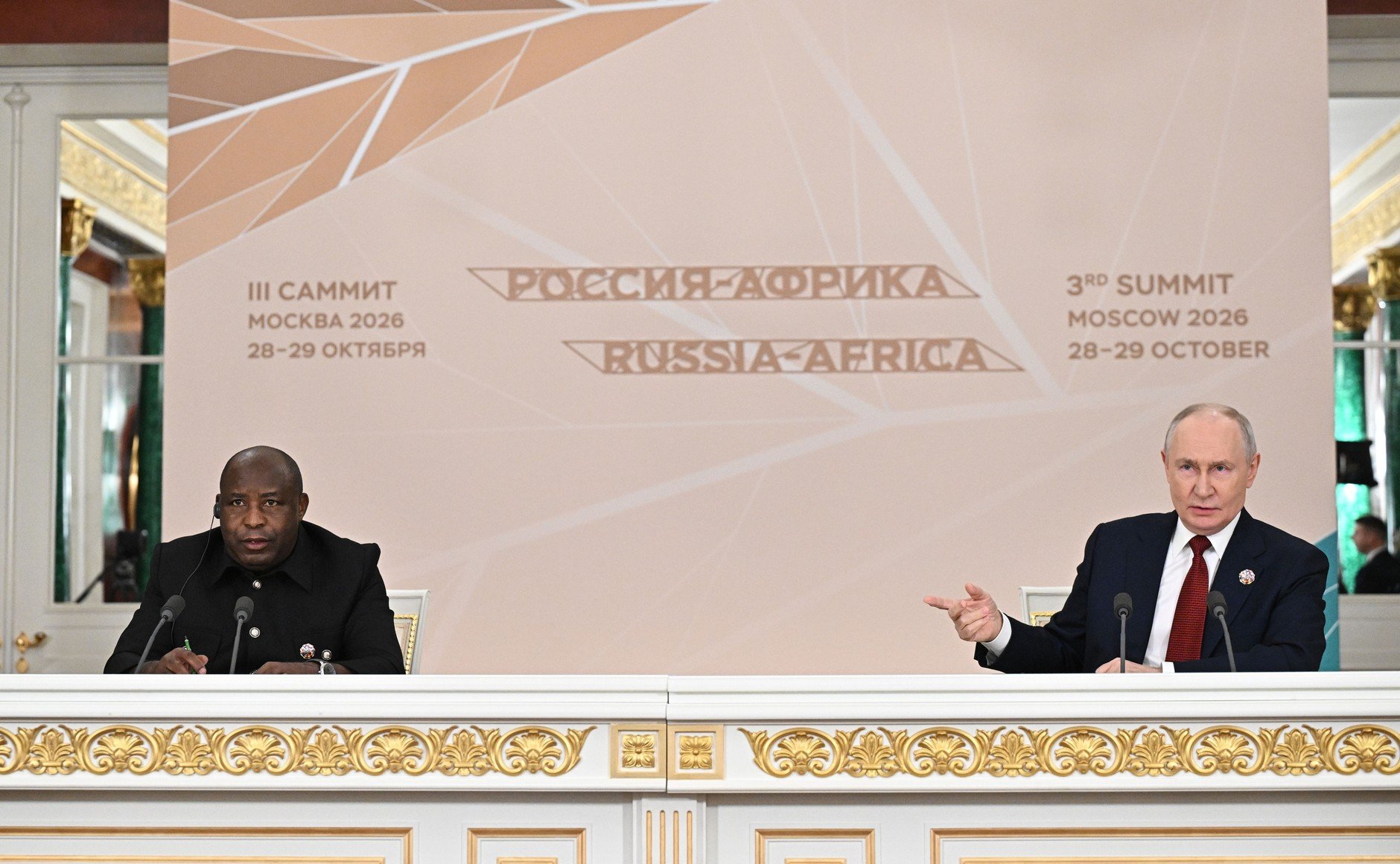 Burundi's President Ndayishimiye and Russia's President Putin seated at a table in front of the Russia-Africa summit banner