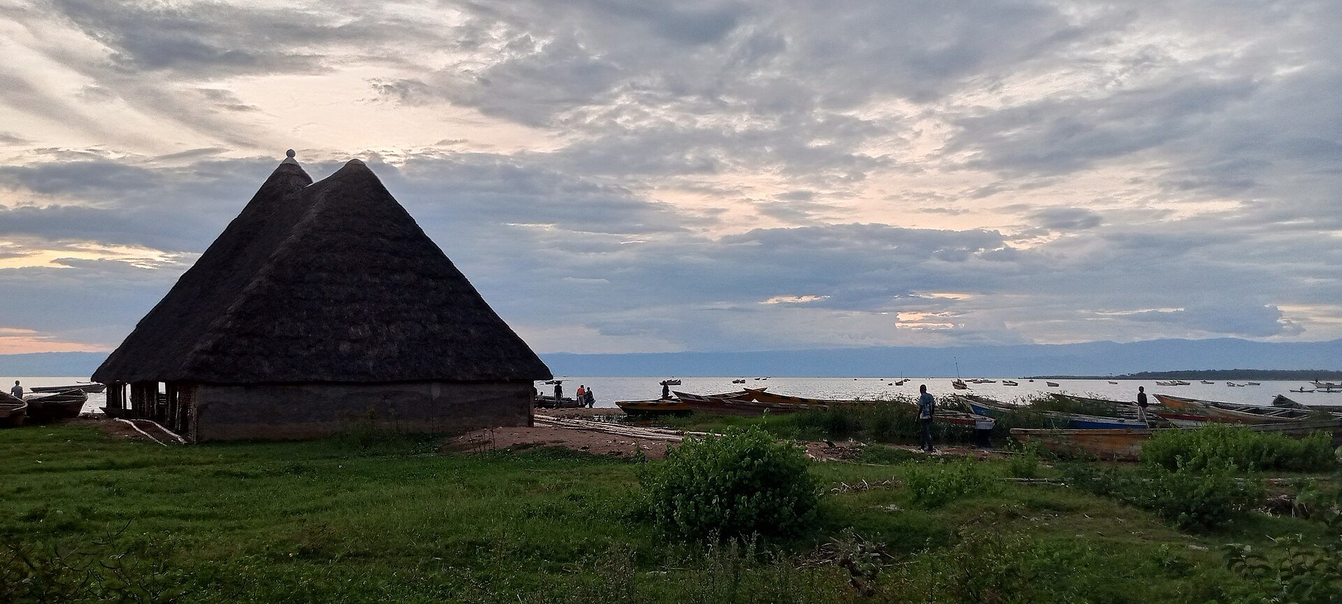 Fishing boats and a thatched building on the shore of Lake Tanganyika in Burundi at dusk