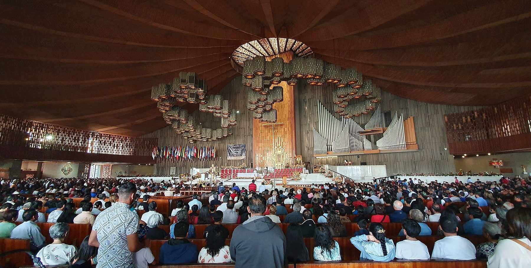 Crowded pews inside the round modern Basilica of Our Lady of Guadalupe in Mexico City, seen from the back