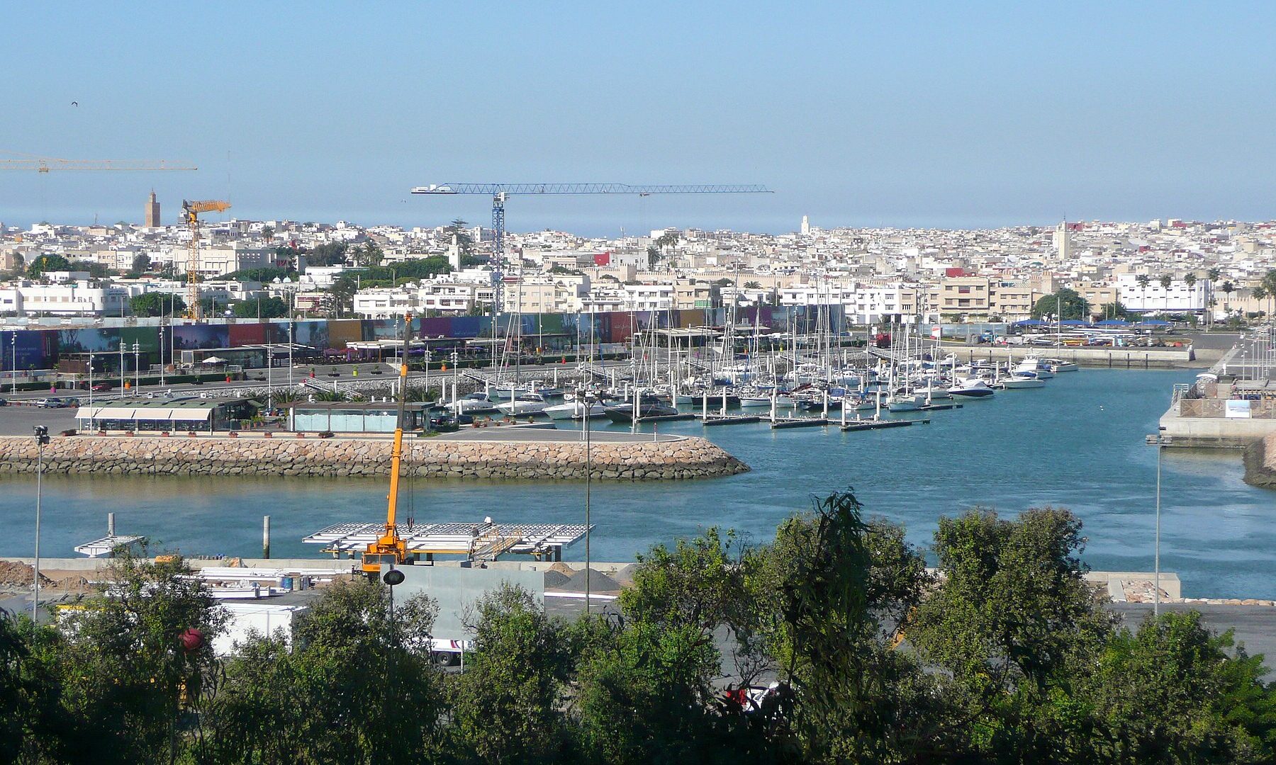 Boats moored in the Bouregreg marina at Salé, seen from Rabat, with the white buildings of Salé and construction cranes behind