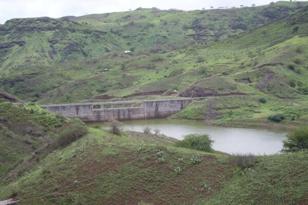 A small concrete dam holding a pond among green terraced hills on Santiago island, Cabo Verde